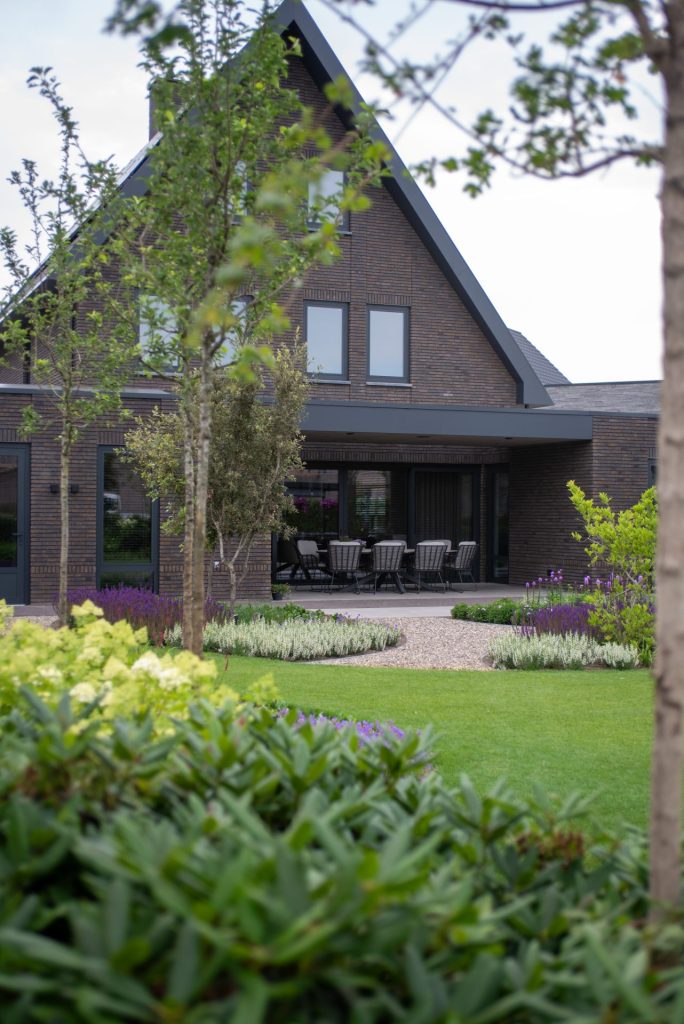 Deze tuin is een buitenruimte waarin elegantie, rust en luxe centraal staan. De tuin kenmerkt zich door organische vormen. Veel groen zoals siergrassen, meerstammige heesters en bomen, geven de tuin een weelderige uitstraling die elk seizoen leeft.